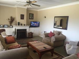 a living room with couches and a table and a tv at Hawley House in Underberg