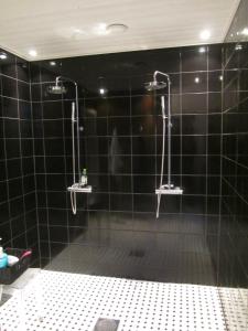 a bathroom with a shower with black tiles at Hotelli Huiskankorpi Boutique Hotel in Nivala
