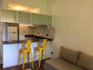 uma cozinha com dois bancos de bar amarelos e um sofá em Guatemala em Buenos Aires