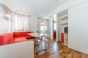 een woonkamer met een rode bank en een tafel bij Mobile Homes Plava Laguna in Pakoštane