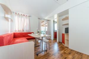 a living room with a red couch and a table at Mobile Homes Plava Laguna in Pakoštane