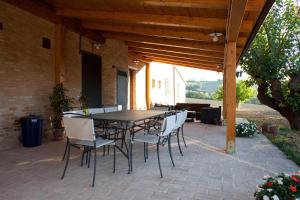 a patio with a table and chairs under a wooden pergola at Casale Talevi in Cartoceto