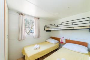 two beds in a small room with a window at Mobile Homes Plava Laguna in Pakoštane