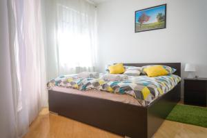 um quarto com uma cama com almofadas amarelas e uma janela em Blue Lake Apartment em Zagreb