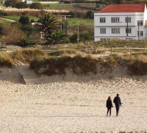 a man and a woman walking on the beach at Playa de Barrañan in Arteixo