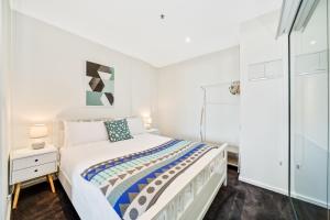 a white bedroom with a bed and a glass door at York Apartments in Adelaide