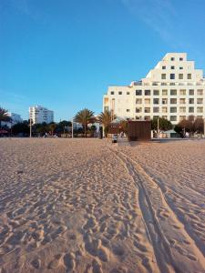 una playa de arena con un edificio en el fondo en Cartaia Apartamento Leste, en Quarteira