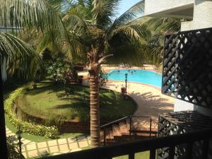 een uitzicht over een zwembad met een palmboom bij Pool and Garden Facing Apartment in Riviera Foothills Near Baga, Arpora in Arpora