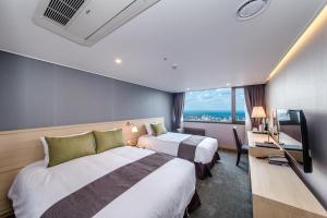 a hotel room with two beds and a television at Hotel Shalom Jeju in Jeju