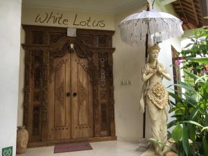 posąg kobiety trzymającej parasol przed drzwiami w obiekcie White Lotus Oasis w mieście Ubud