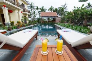 a pool with two beds and drinks on a table at Lama Villa Hoi An in Hoi An
