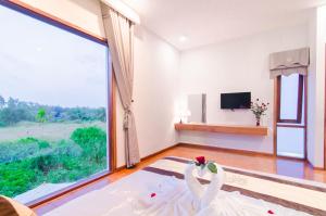 una habitación con una ventana grande y una pareja de bodas en el suelo en Green World Hoi An Villa en Hoi An