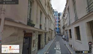 an empty street in a city with buildings at Le Merlot du Marais in Paris