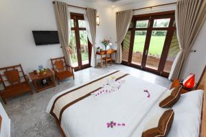 a bedroom with a large white bed with flowers on it at Lama Villa Hoi An in Hoi An