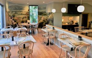 um restaurante com mesas e cadeiras e uma grande pintura na parede em Baileys Parkside Motel by VetroBlu em Perth