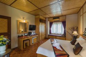 
a hotel room with a bed, table, chairs and a tv at Coral Hotel Bangsaphan in Bang Saphan
