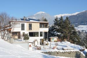 a house in the snow with mountains in the background at Ferienwohnungen Unterluimes in Telfes im Stubai