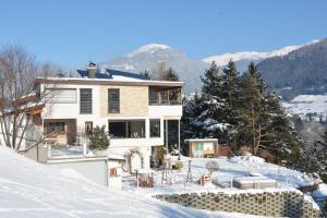 ein Haus im Schnee mit Bergen im Hintergrund in der Unterkunft Ferienwohnungen Unterluimes in Telfes im Stubai