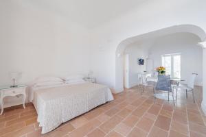 a white bedroom with a bed and a table at Casa Malu in Positano
