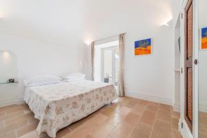 a white bedroom with a bed and a window at Casa Malu in Positano