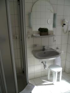 a bathroom with a sink and a stool and a mirror at Hotel Kronprinz in Kulmbach