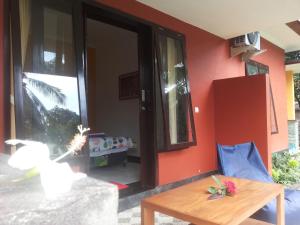 a living room with a table and a red wall at Gede's Homestay in Tejakula