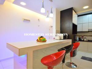 a kitchen with a counter and two red chairs at Seri Endon Apartment in Shah Alam