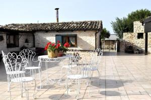 a patio with white chairs and a table with flowers at Tenuta Tannoja in Andria