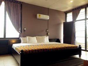 a bedroom with a bed in a room with windows at Kokodo Guest House in Cape Coast