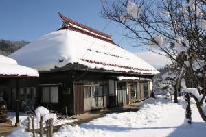 une maison recouverte de neige avec un toit dans l'établissement Madarao Farm, à Nakano
