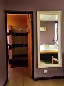 a bathroom with a mirror and a bed in a room at Kokodo Guest House in Cape Coast