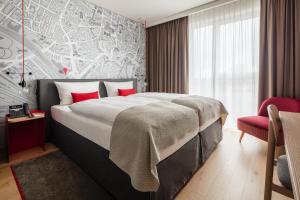 Un dormitorio con una cama grande y una silla roja. en IntercityHotel Braunschweig, en Brunswick