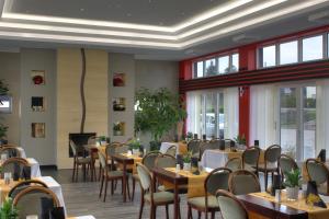 a dining room with tables and chairs and windows at Hotel Eleganz in Rustow