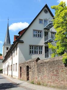 a white house with a brick wall and a church at Bildungshaus Neckarelz in Mosbach