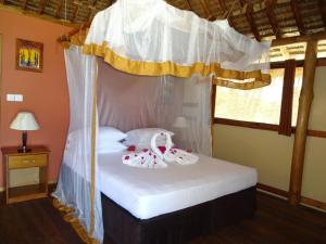 a bedroom with a canopy bed with two dolls on it at Barry's Beach Resort Pangani in Mkwaja