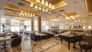 a restaurant with tables and chairs and a piano at Apartment Pearl of Arcadia in Odesa