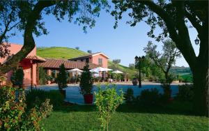 une maison avec un arbre dans une cour dans l'établissement Country Hotel & Resort I Calanchi, à Ripatransone