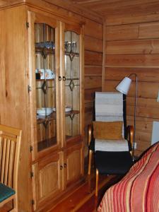 Un dormitorio con una cabaña de madera con una cama y una silla en Metsolan pihapiiri, en Multia
