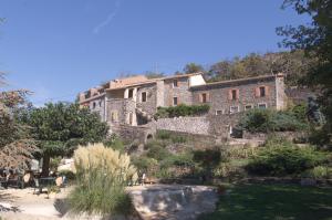 a large stone building on a hill with a garden at Logis Hôtel-restaurant La Mère Biquette in Saint-Pons
