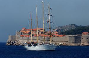 a white boat in the water near a castle at Apartment Maja in Dubrovnik