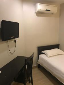 a bedroom with a bed and a desk and a tv at SE Hotel in Butterworth