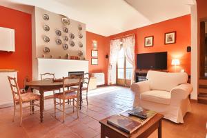 un soggiorno con pareti arancioni, tavolo e sedie di Scuderie I Berroni a Racconigi
