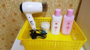 a yellow basket with two bottles and a hair dryer at Guesthouse Spring Flower in Seogwipo