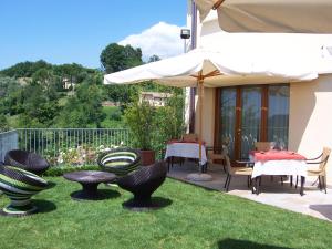 eine Terrasse mit Stühlen, Tischen und einem Sonnenschirm in der Unterkunft Locanda da Gerry in Castelcucco