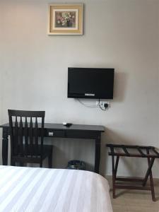 a bedroom with a desk with a tv and a chair at SE Two Hotel in Butterworth