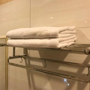 una pila de toallas en un estante del baño en SE Two Hotel, en Butterworth
