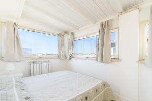 - une chambre blanche avec un lit et 2 fenêtres dans l'établissement Villa Martina, à Fregene