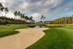 a golf course with palm trees and a pond at GolfBay Villa in Senica