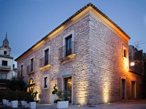 un grand bâtiment en briques avec des lumières sur lui dans l'établissement Abraxia B&B, à Comiso