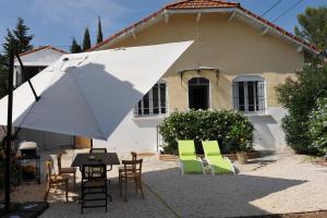 een tafel en stoelen en een parasol voor een huis bij Villa au centre de Nîmes in Nîmes